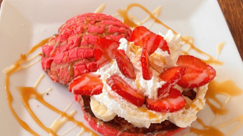 Pink concha French toast with whipped cream, strawberries and caramel.